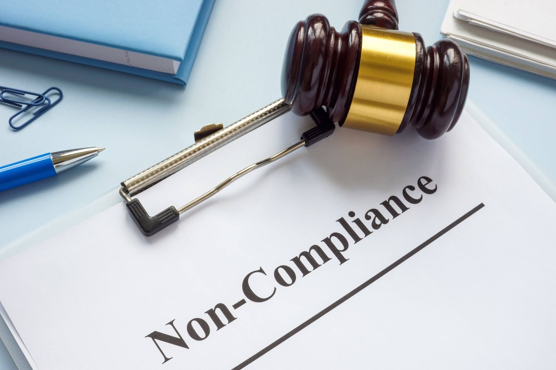 Clipboard with document about non-compliance and gavel.